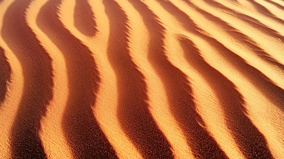 Close-up shot of the patterned texture of sand in an empty desert