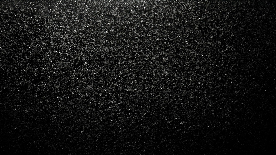 Black texture with scattered grainy particles