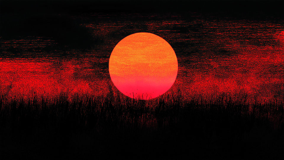 Red sun setting over grassy fields