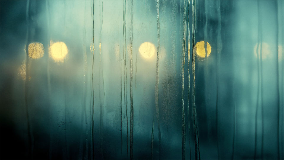 Moody rainy window with soft city light patterns