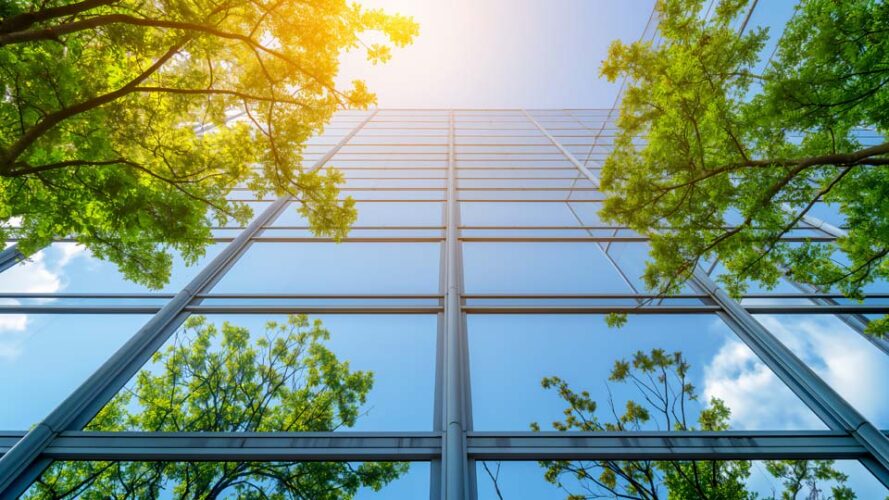 A glass building with green trees and a blue sky