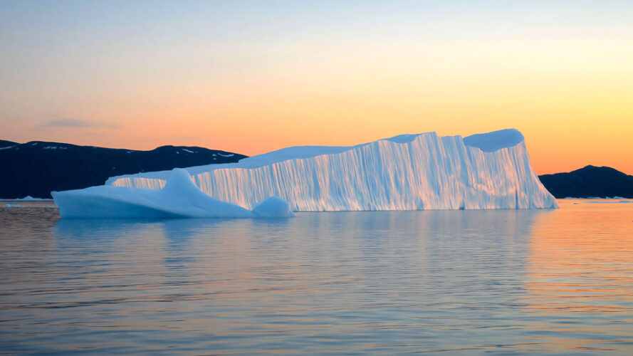 Iceberg floating in the water at sunset