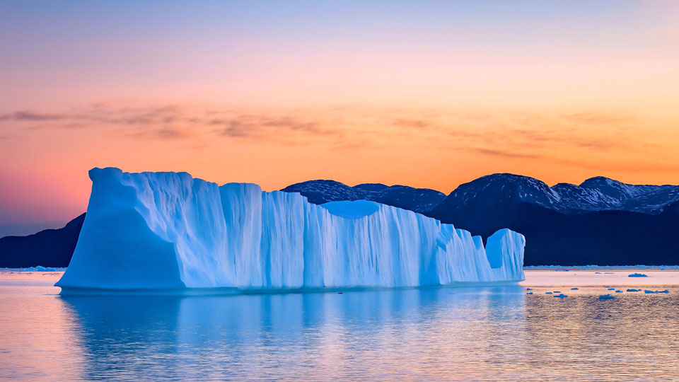Iceberg floating in the water at sunset
