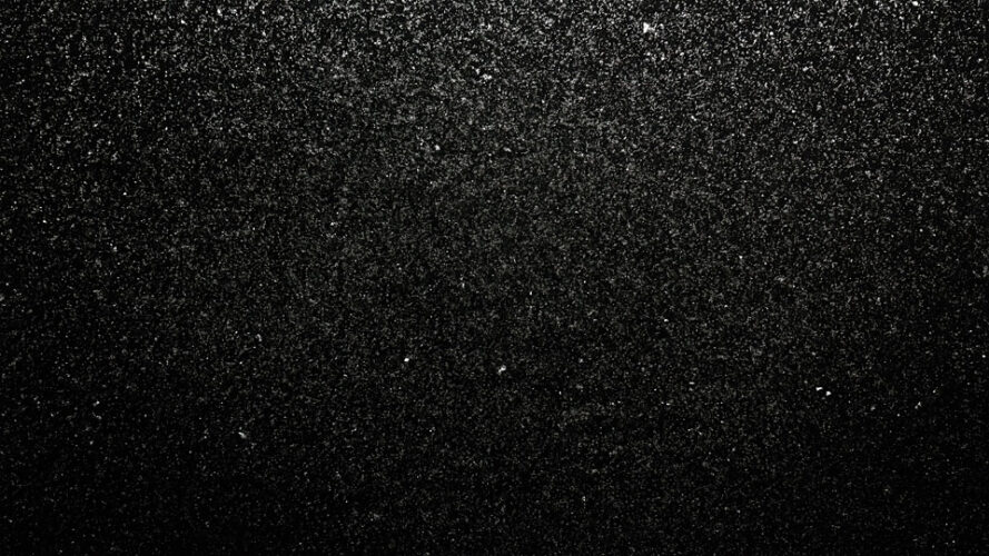 Black texture with scattered grainy particles