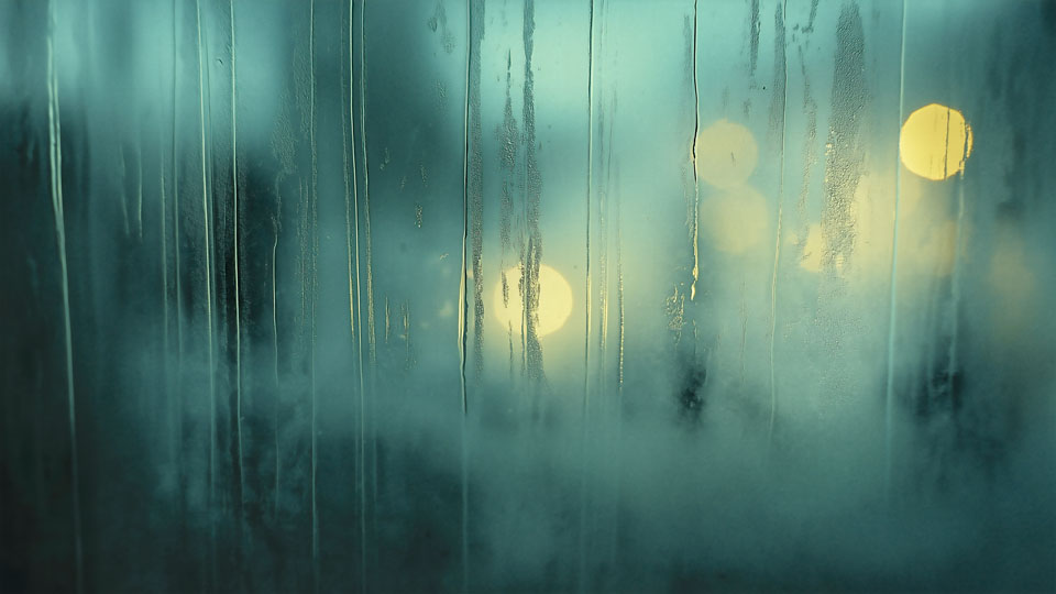Foggy rainy window and glowing cityscape